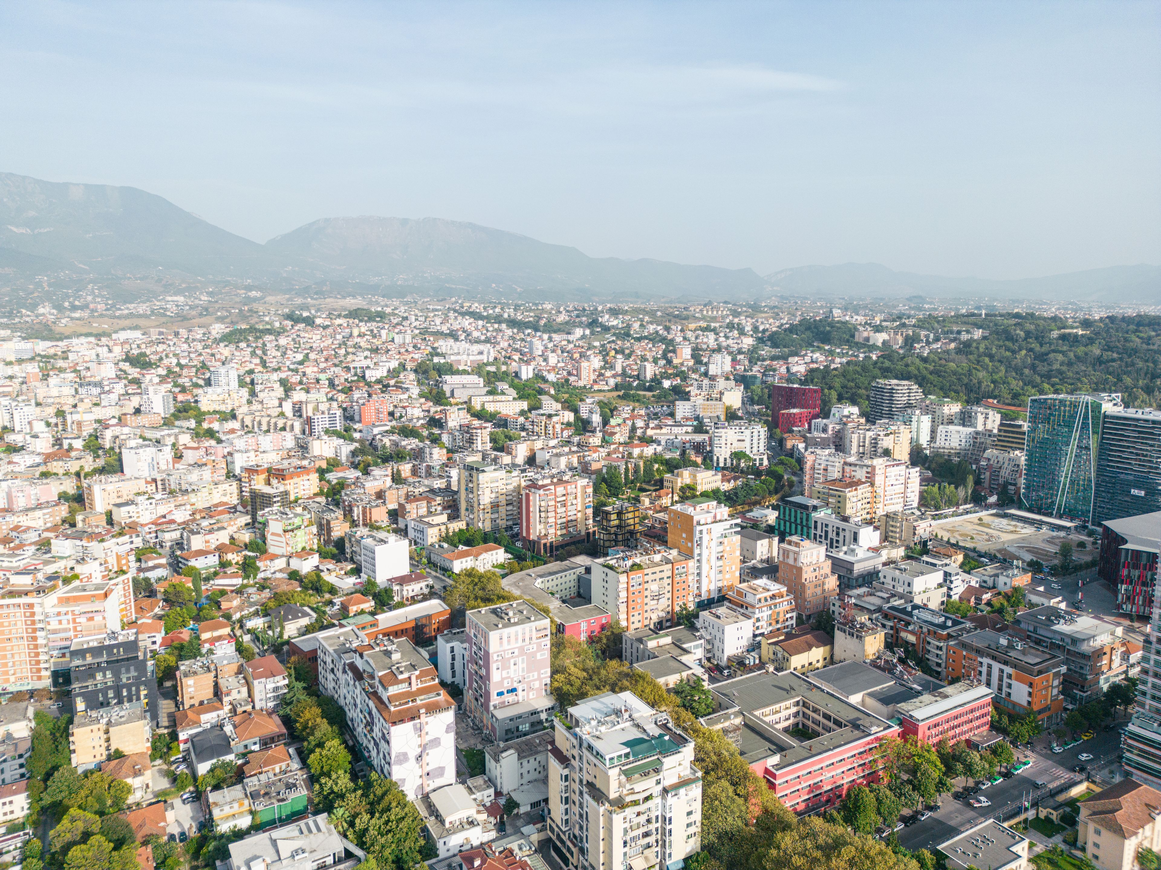 Një pamje panoramike e Tiranës, duke shfaqur një përzierje qiellgërvishtësesh moderne, ndërtesash shumëngjyrëshe dhe maleve përreth.