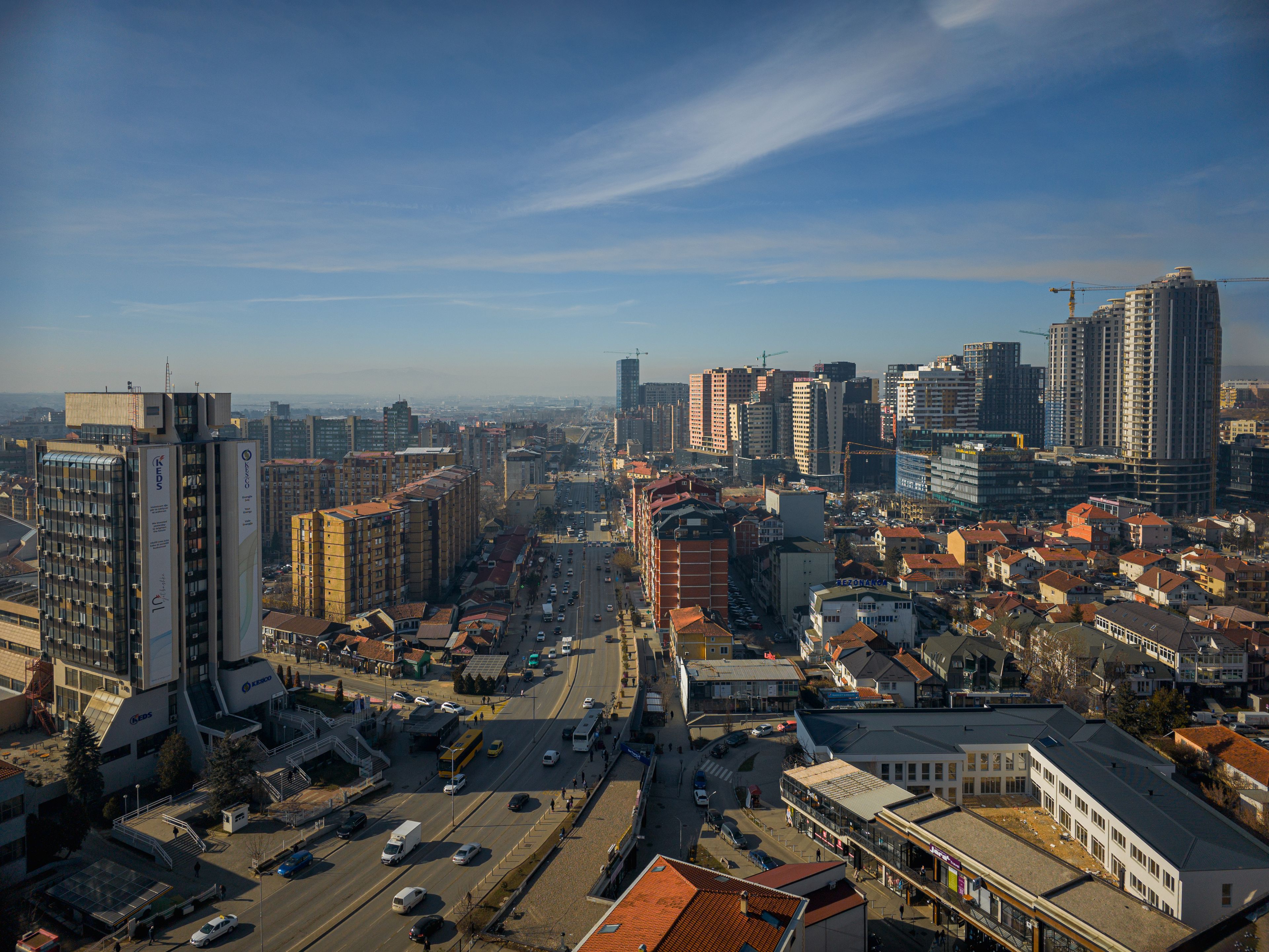 A dynamic view of Prishtina, showcasing a mix of modern skyscrapers, older buildings, and busy streets, reflecting the city’s rapid growth.